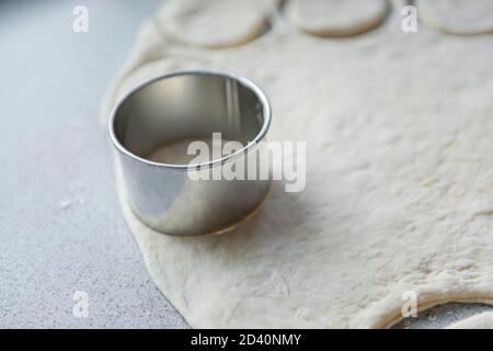 Vorbereitung des Teigs zum Backen, Einfrieren, Sculpting und andere Rohlinge - ein großes Stück des Teigs liegt auf dem Tisch und der Koch schneidet smal aus Stockfoto