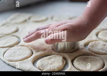 Vorbereitung des Teigs zum Backen, Einfrieren, Sculpting und andere Rohlinge - ein großes Stück des Teigs liegt auf dem Tisch und der Koch schneidet smal aus Stockfoto