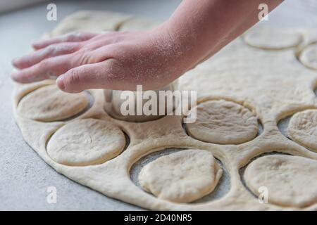 Vorbereitung des Teigs zum Backen, Einfrieren, Sculpting und andere Rohlinge - ein großes Stück des Teigs liegt auf dem Tisch und der Koch schneidet smal aus Stockfoto