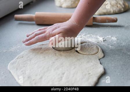Vorbereitung des Teigs zum Backen, Einfrieren, Sculpting und andere Rohlinge - ein großes Stück des Teigs liegt auf dem Tisch und der Koch schneidet smal aus Stockfoto