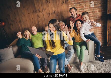 Foto der ganzen Familie Acht Personen sammeln Kuscheln Welle Hand Kleines Mädchen Tochter halten Netbook Remote Videocall Gruß relativ Sitzsofa Stockfoto