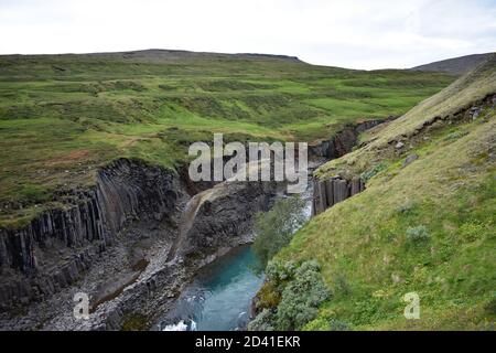 Studlagil Canyon im Nordosten Islands von der Westseite aus gesehen bei der Farm Grund. Das Gelände fällt steil nach unten zu den Basaltsäulen. Stockfoto