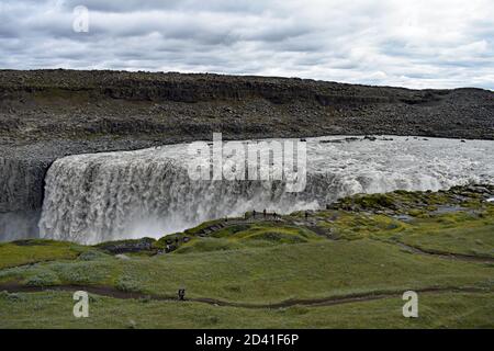 Dettifoss Wasserfall im Nordosten Islands. Besucher und Touristen können gesehen werden, wie sie sich entlang des Weges wundern, der dem Rand des Jokulsargljufur Canyon folgt. Stockfoto