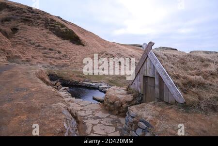 HRUNALAUG THERMALQUELLEN, ISLAND - 10. Dez 2018: Die Hrunalaug, oder Hruni Geothermie Quellen, sind eine seidenbare Thermalquelle mit einem kleinen hölzernen Umkleideraum in IC Stockfoto