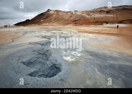 Námafjall Berg und Hverir Geothermie Gebiet in der Nähe des Lake Myvatn in Nordisland. Besucher wandern zwischen den grau kochenden Schlammbecken und der orangefarbenen Landschaft. Stockfoto