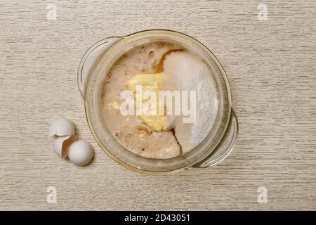 Eine Mischung aus Milch, Eiern, Butter, Zucker, Salz, Backpulver, Vanillin und Hefe in einem durchsichtigen Glaskasserolle. Stockfoto