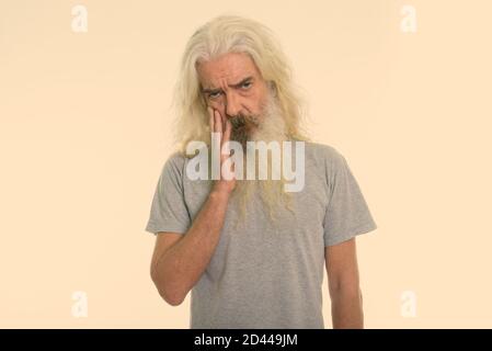 Studio shot der älteren bärtigen Mann mit der Hand im Gesicht stören suchen Stockfoto