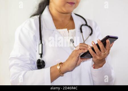 Indische Ärztin prüft auf ihrem Handy bei einem Arzt Klinik in Kalkutta Stockfoto