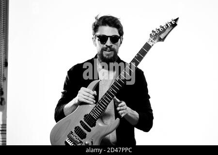 Ein Mann mit einer Gitarre Emotionen Musik Spiel Performance Leder Jacke Sonnenbrille Licht Hintergrund Stockfoto