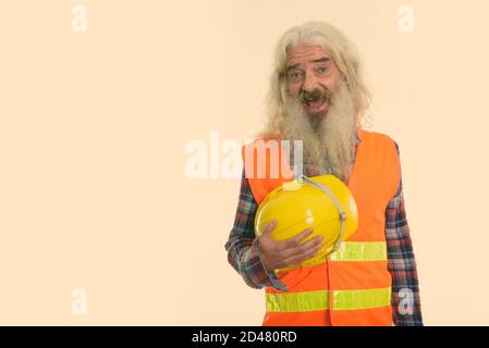 Studio shot von Happy älterer bärtiger Mann Bauarbeiter lächelnd, während sie Schutzhelm Stockfoto
