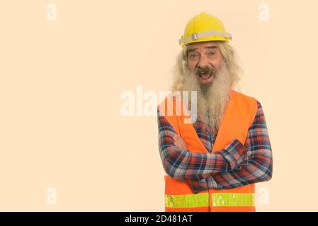 Studio shot von Happy älterer bärtiger Mann Bauarbeiter lächelnd mit gekreuzten Armen Stockfoto