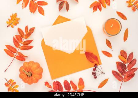 Kreative Herbst flach Lay Komposition auf weißem Hintergrund mit orange und roten Blättern, Kerze, Kürbis, und Umschlag mit Kopierraum Stockfoto
