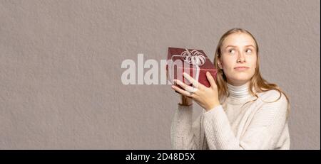Eine Nahaufnahme einer jungen Frau, die ein Geschenk hält Ihr Kopf Stockfoto