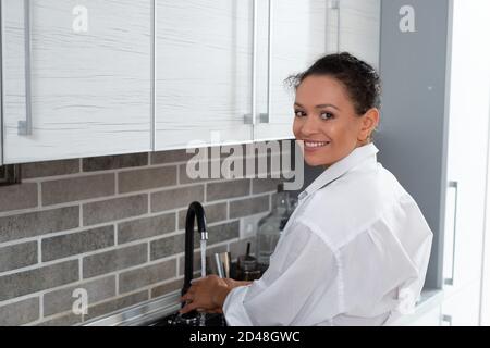 Die junge Küchenchefin wäscht Pilze unter dem Wasserhahn, schaut uns an und lächelt. Stockfoto