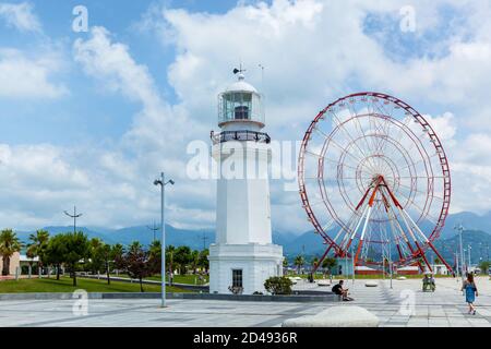 Batumi Georgia 25. Juni 2017: Riesenrad und alter Leuchtturm am Ufer in Batumi. Moderne Gebäude und touristische Entwicklung in Batumi, Georgien Stockfoto