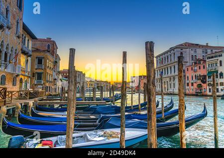 Gondeln, die an der Anlegestelle des Canale Grande in Venedig festgemacht sind. Holzpfosten und barocke Gebäude entlang des Canal Grande. Erstaunliche Venedig Stadtbild bei Sonnenuntergang Dämmerung. Region Venetien, Italien Stockfoto