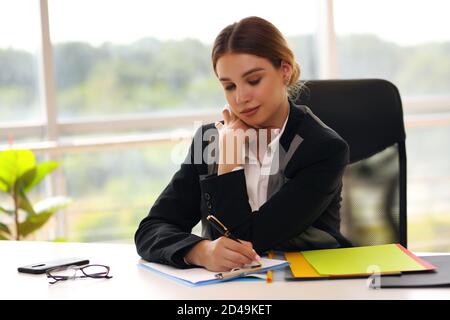 Junge glücklich lächelnde Geschäftsfrau arbeitet im Büro Stockfoto