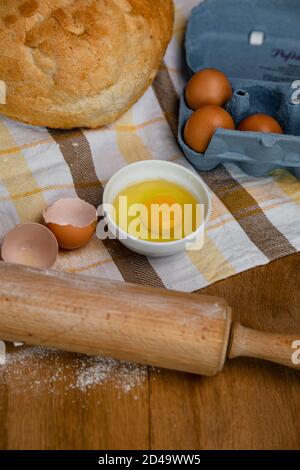 Frisches Brot zusammen mit Tomaten und Eiern auf ein Handtuch gelegt. Bäckerei - Gold rustikale knusprige Brote. Stillleben von oben (Draufsicht, Stockfoto