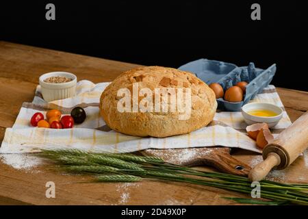 Frisches Brot zusammen mit Tomaten und Eiern auf ein Handtuch gelegt. Bäckerei - Gold rustikale knusprige Brote. Stillleben von oben (Draufsicht, Stockfoto