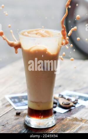 Eine Tasse Eismilchkaffee auf einem hölzernen Kaffeetisch. Brauen Sie frischen Kaffee für Kaffeepausen während des Tages Stockfoto