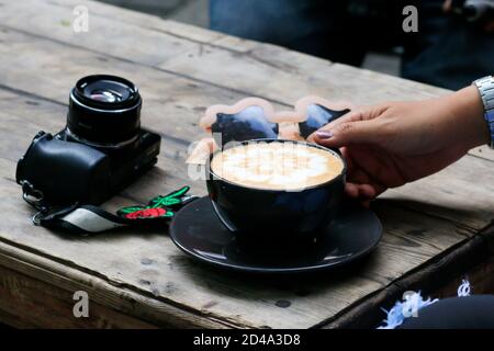 Eine Tasse Eiskaffee Latte auf einem hölzernen Café-Tisch. Brew frischen Latte Art Kaffee für Kaffeepausen während des Tages Stockfoto