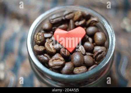 Kaffeebohnenbehälter mit rotem Origami Herz geformten Papier auf der Oberseite. Gerösteter Kaffee mit einem frischen Aroma bereit, gebraut werden Stockfoto