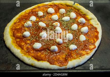 Pizza auf Schiefer mit Tomatensauce, Mozzarella und Oregano Stockfoto