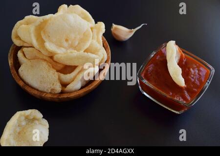 Frisches Krurupuk auf dunklem Hintergrund.Garnelencracker oder Garnelen Chips mit Ketchup und Knoblauch Stockfoto