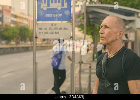 Kahl senior touristische Mann denken, während an der Bushaltestelle in Bangkok Thailand warten Stockfoto