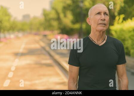 Kahl senior touristische Mann denken an der Seite der Straße an der ruhigen Park in Bangkok, Thailand Stockfoto