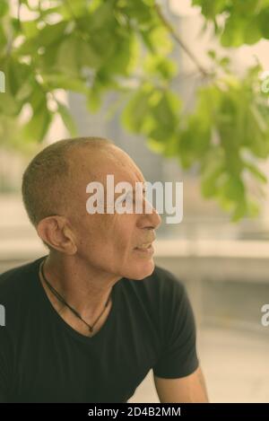 Profil anzeigen von Kahl senior touristische Mann denken und Entspannen unter den Baum in der Stadt Stockfoto