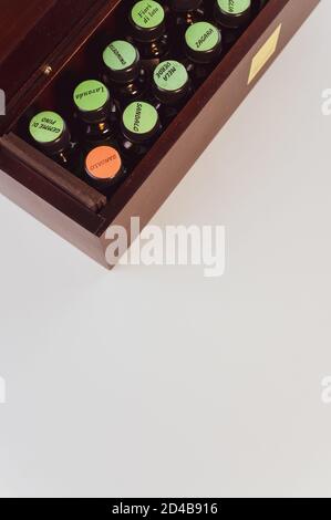 Vertikale Aufnahme von verschiedenen ätherischen Ölen in einer Holzkiste, auf einer weißen Oberfläche Stockfoto