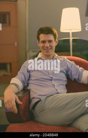 Junge gut aussehender Geschäftsmann Entspannung im Hotel Lobby Stockfoto