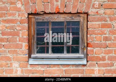 Altes verschlossenes Fenster mit schützendem Metallgitter in grungy Ziegelwand, Hintergrund Foto Textur Stockfoto