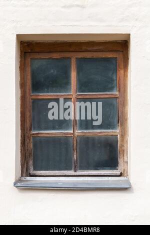 Altes staubiges Fenster mit Holzrahmen in einer weißen Steinwand, Hintergrund Foto Textur Stockfoto