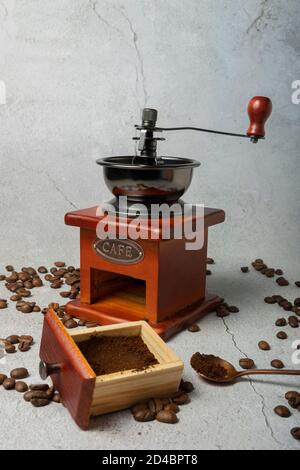 Selektiver Fokus. Manuelle retro Kaffeebohnenmühle. Dunkles Holz auf hellgrauem Hintergrund. Mit Cafe in Metallbuchstaben geschrieben Stockfoto