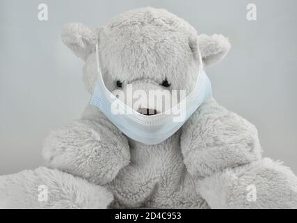 Teddybär weiches Spielzeug in schützender medizinischer Maske. Weißer Bär Kind Spielzeug als Coronavirus und Atemwegserkrankung Präventivkonzept Stockfoto