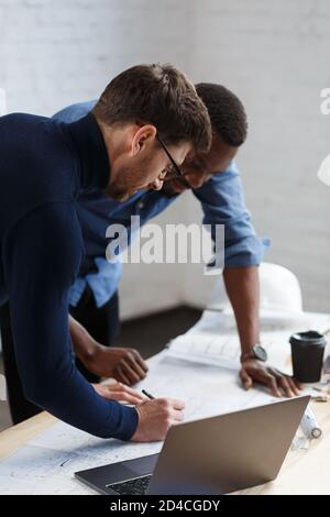 Multiracial Engineer Team arbeitet im Büro mit blauen Drucken und Architektengeräten, die Bauvorhaben skizzieren, diskutieren und planen. Partner Stockfoto