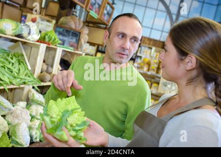 Mann, der saisonales Gemüse im lokalen Lebensmittelgeschäft kauft Stockfoto