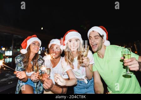 Junge Freunde feiern das neue Jahr mit Champagner und Wunderkerzen im Freien Nachts Stockfoto