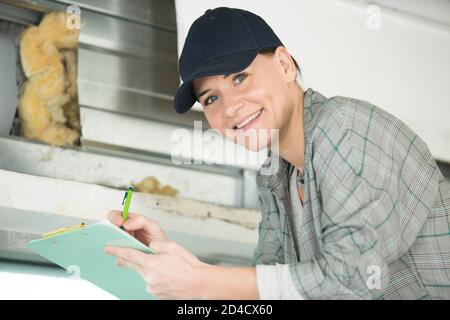 Glückliche Frau, die mit Bleistift auf einer Leiter steht Stockfoto