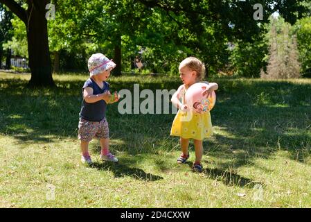 Zwei kleine Kinder spielen in einem Park mit einem Ball Stockfoto