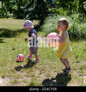 Zwei kleine Kinder spielen in einem Park mit einem Ball Stockfoto