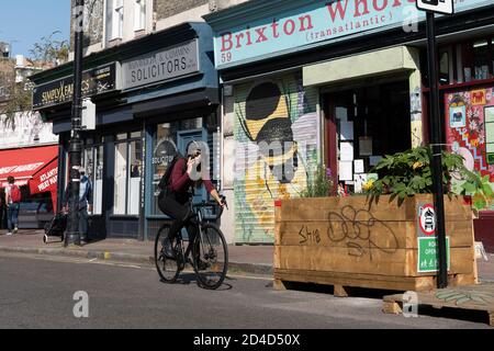 Eine Radfahrerin, die ein Mobiltelefon benutzt, während sie mit dem Fahrrad auf der Atlantic Road unterwegs ist.die Schließung erfolgt am 16. September 2020 in Brixton im Vereinigten Königreich. P Stockfoto