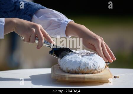 Dresden, Deutschland. Okt. 2020. Johanna Meitzner, das 26. Dresdner Stollenmädchen, schneidet den einen Weihnachtsstollen während ihres Aufführens im Schlosspark Pillnitz. Der 21-jährige Bäckerlehrling ist für ein Jahr Botschafter des Dresdner Christstollens im Auftrag der Dresdner Stollenbäcker. Quelle: Robert Michael/dpa-Zentralbild/ZB/dpa/Alamy Live News Stockfoto