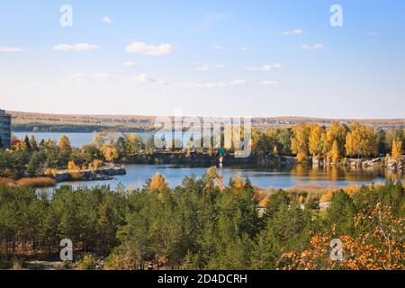 Schöner alter Granitbruch mit klarem Wasser im indischen Sommer. Auf der Rückseite befindet sich der Shershni-Stausee. Tscheljabinsk, Russland. Stockfoto