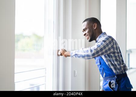 Junger Afrikanischer Reparateur In Overalls Fenster Installieren Stockfoto