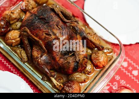 Eine Nahaufnahme einer knusprig gebackenen Gans in eigenem Fett mit Kartoffeln und Äpfeln, zum Weihnachtsessen. Stockfoto