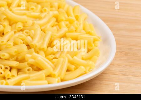 Teller voll mit köstlichen Macaroni und Käse auf einem hölzernen Hintergrund Stockfoto