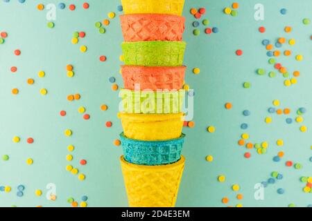 Helle bunte Eis Waffelkegel auf blauem Hintergrund mit verstreuten Konfetti Zucker bestreut Stockfoto
